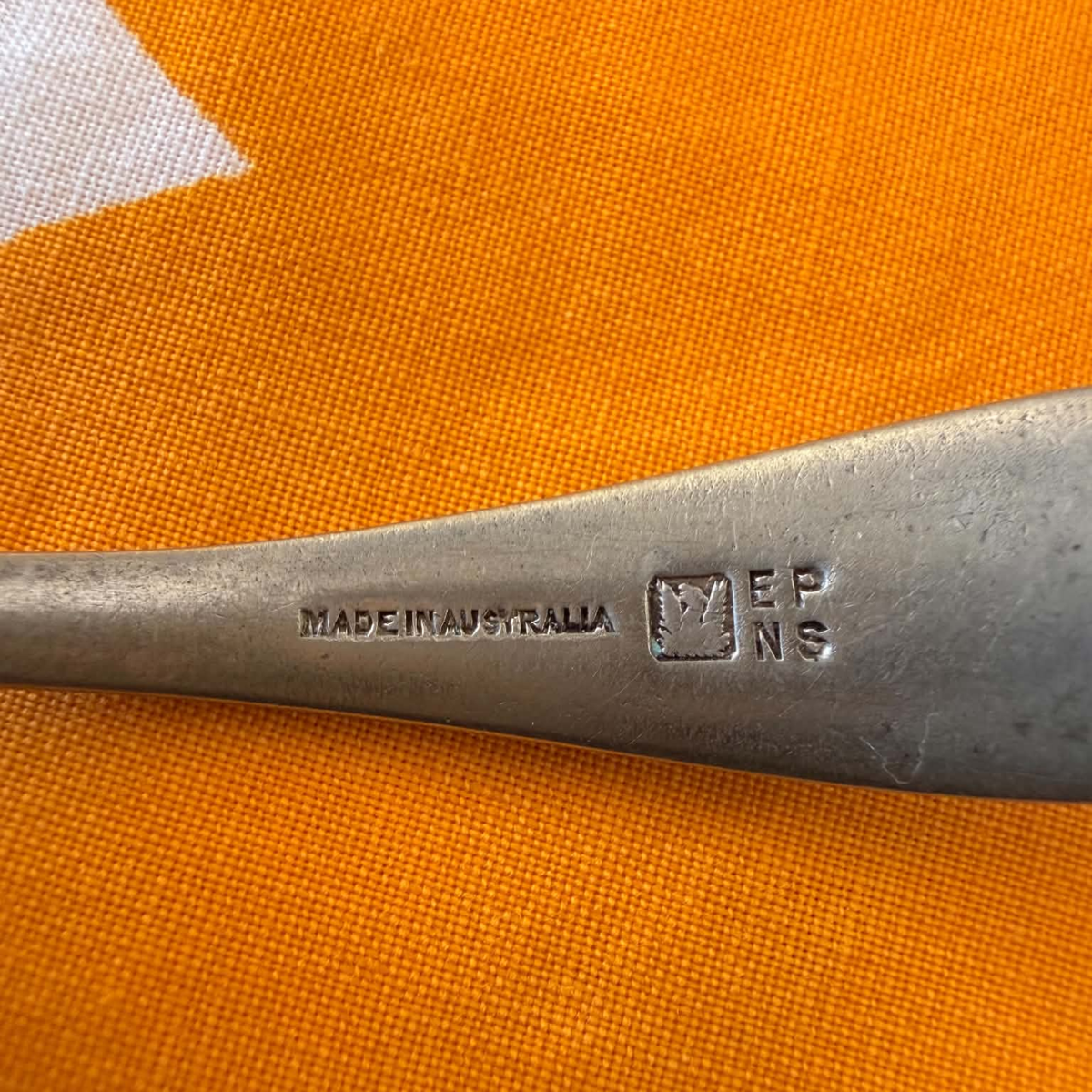  makers marks for A vintage silver plated tea strainer spoon with a perforated spoon bowl, resting on a white tablecloth with yellow and orange polka dots. 