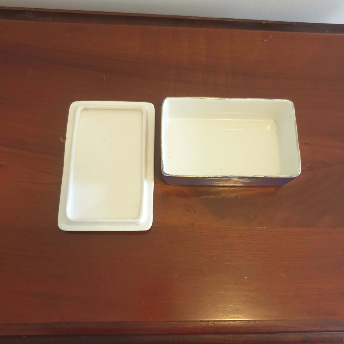 A white rectangular ceramic dish with a matching lid, placed on a dark brown wooden table.