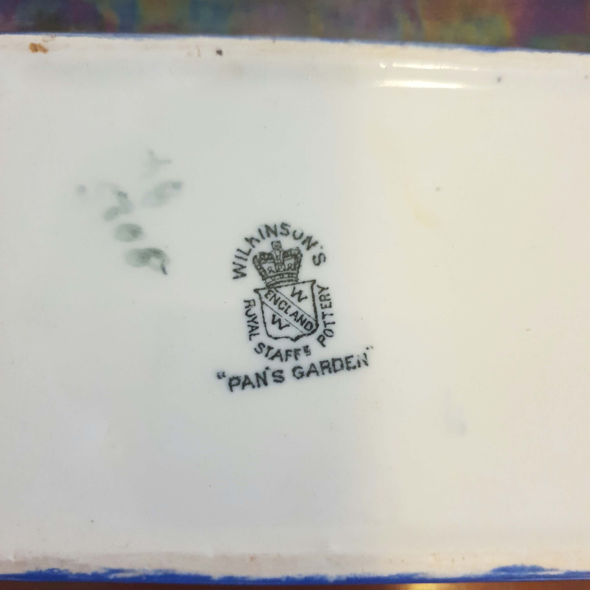 Close-up of the underside of a white ceramic plate or dish, showing a printed Wilmsen's Royal Stafford pottery crest and the text 'Pan's Garden'.
